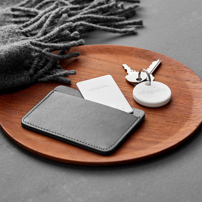 Chipolo Card Bluetooth GPS tracker 2-pak hvid i grå pung, nøgler med rund tracker, grå tørklæde.