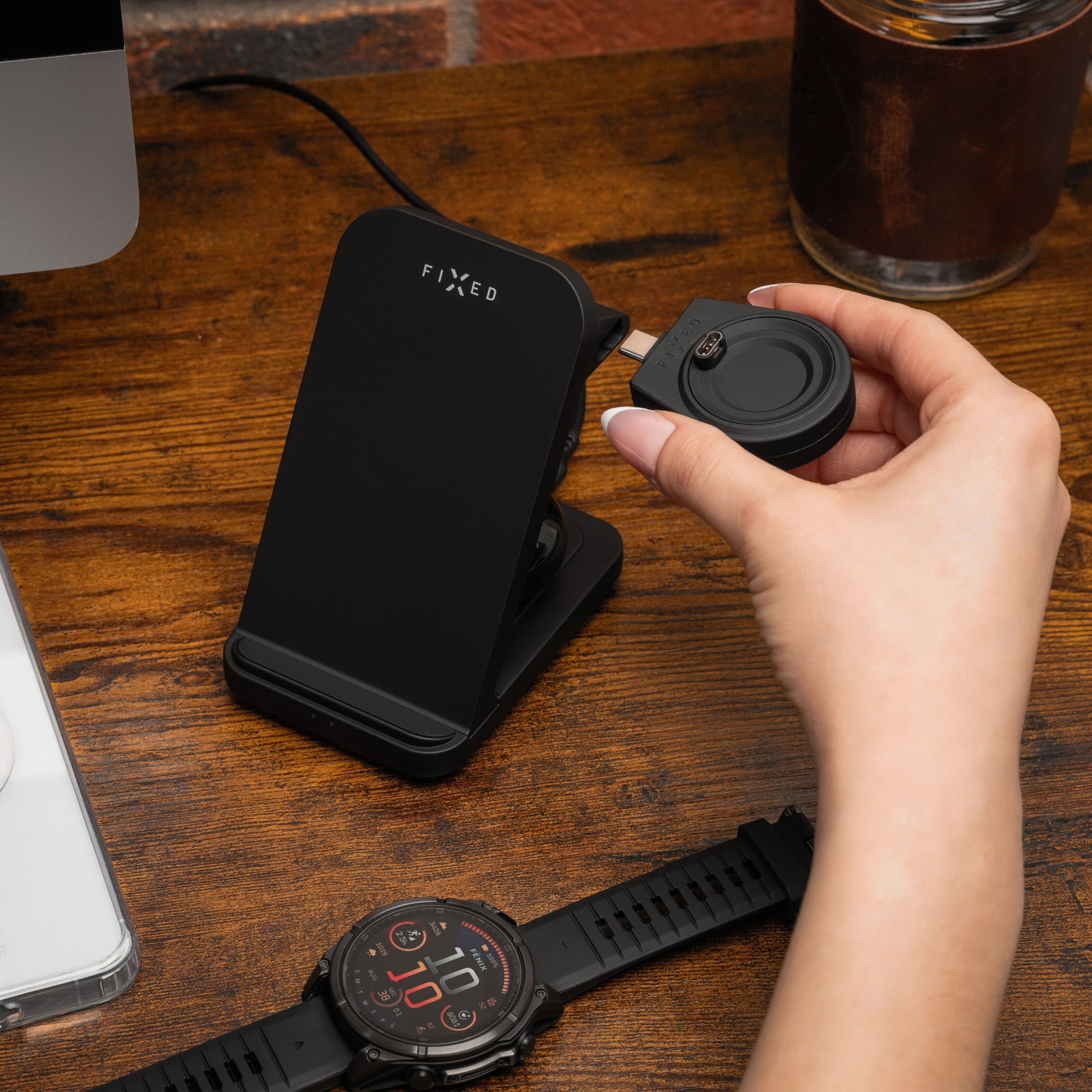 Sort Fixed 3-i-1 trådløs opladningsstation til Garmin på træbord, smartwatch synlig i forgrunden.