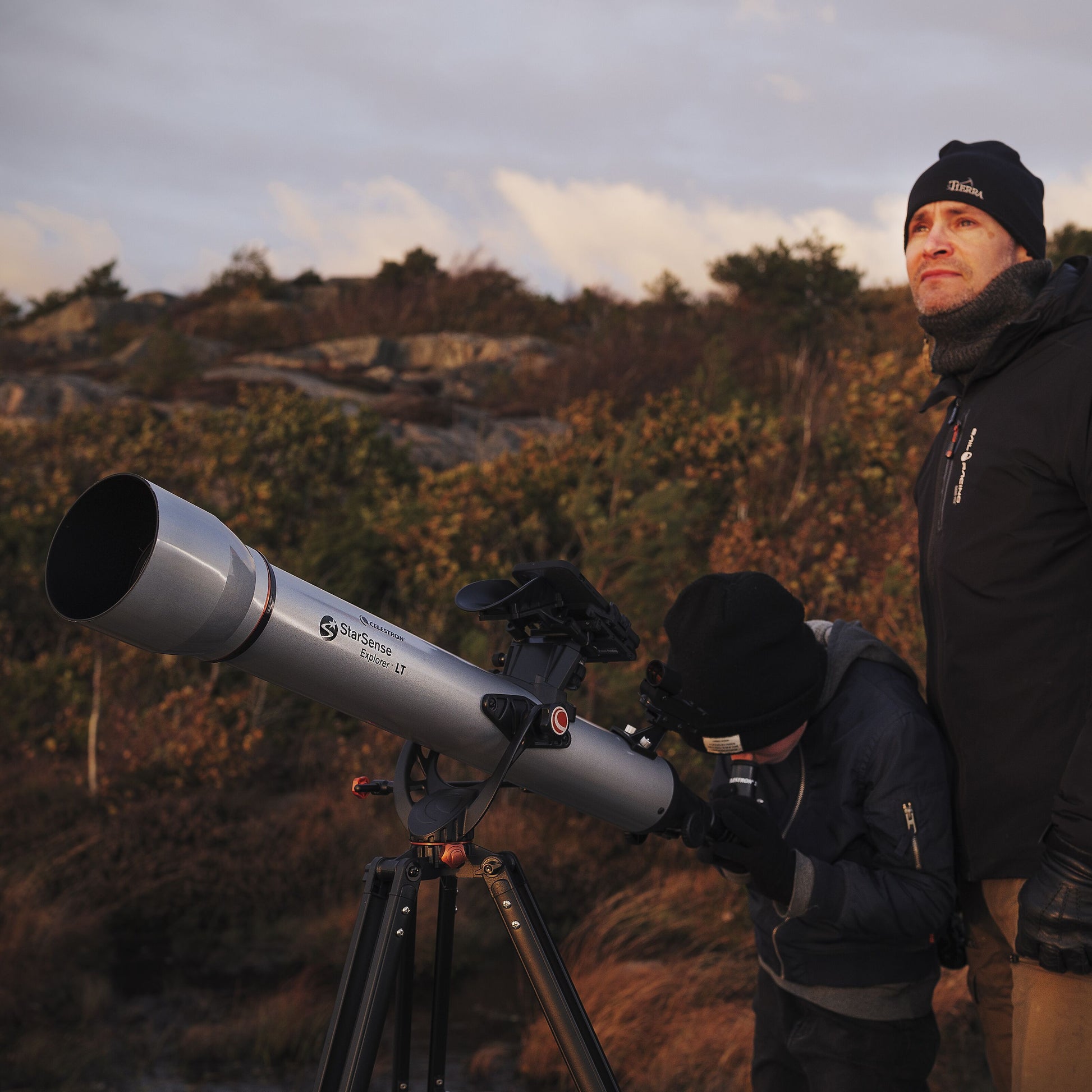Celestron Powerseeker 60 AZ teleskop på stativ udendørs, en person bruger teleskopet, en anden står ved siden af.