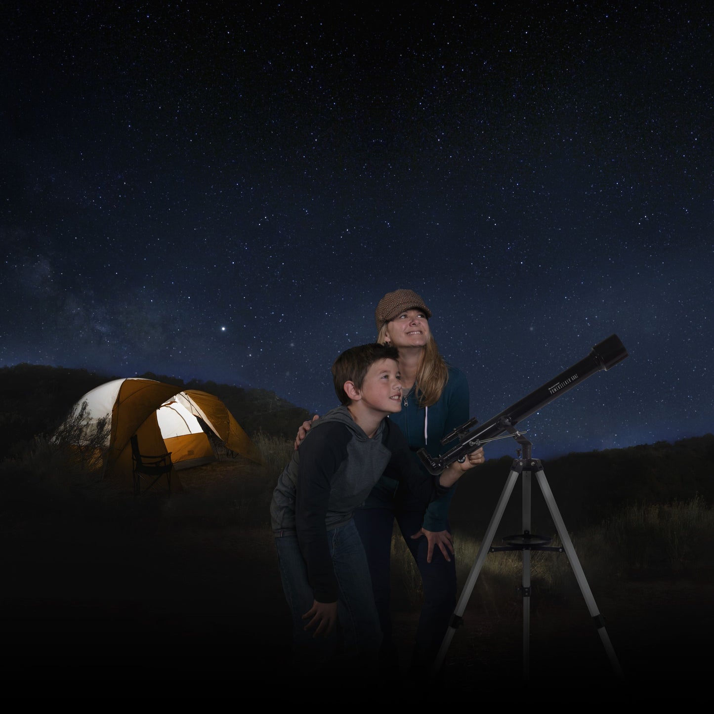 Celestron Powerseeker 60 AZ teleskop med azimutal montering i brug om natten, telt svagt oplyst i baggrunden.