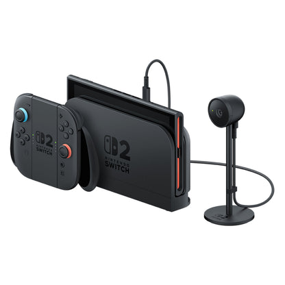 Nintendo Switch til kamera 2, sort konsol i dock, to løse controllere og lille stander-monteret kamera med kabel.