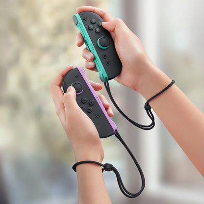 Nintendo Joy Con 2 Par lyse lilla og lysegrønne controllere med håndledsremme, holdes i hænder, motion control vises.