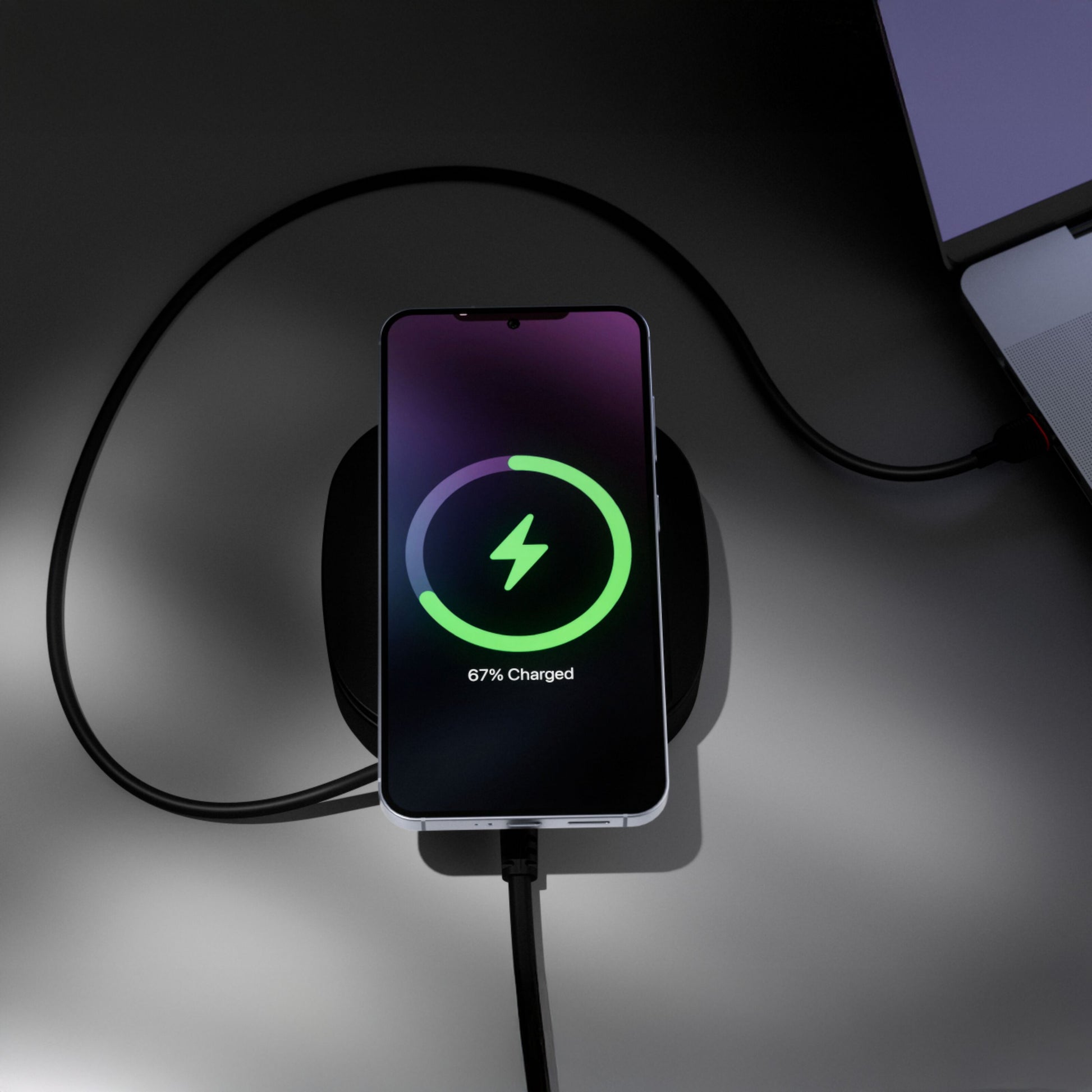 USB-C/Qi2 2i1 80W oplader lader smartphone trådløst på pad (67 batteri, grønt ikon), USB-C tilsluttet laptop.