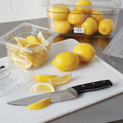 Citroner, citronbåde og kniv på skærebræt ved siden af plastbokse mærket med Dymo Holdbar D1-mærketape 12 mm.