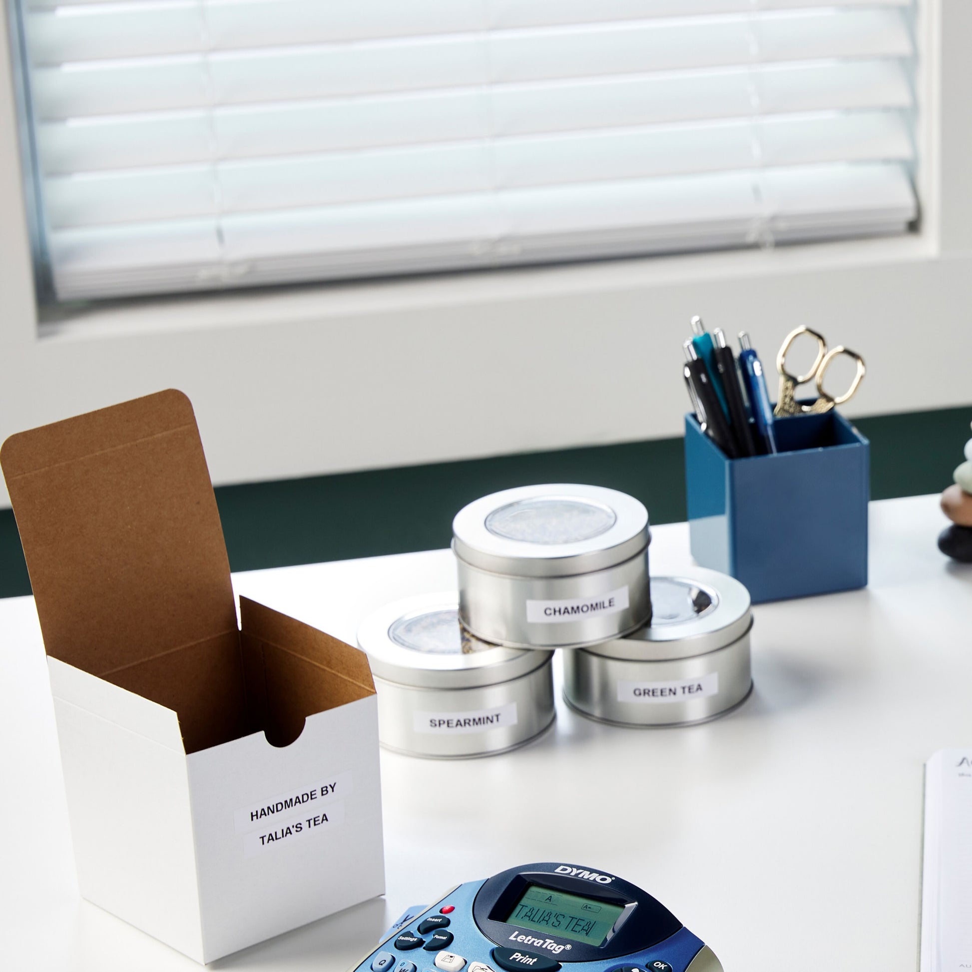 Dymo Letratag mærkemaskine printer TALIAS TEA på 12 mm hvid plastikmærketape ved æske HANDMADE BY TALIAS TEA, te dåser Chamomile, Spearmint, Green Tea.
