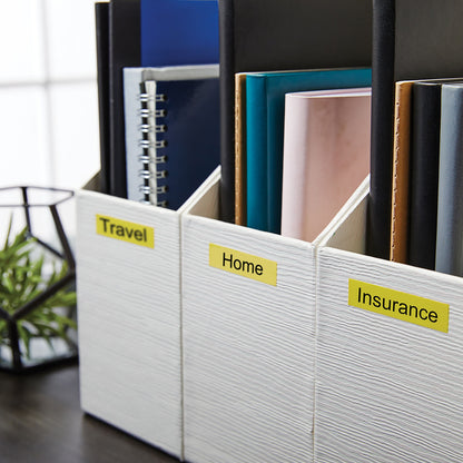 Tre hvide teksturerede mappeholdere med gule Dymo 12 mm labels "Travel", "Home" og "Insurance", fyldt med farvestrålende mapper.