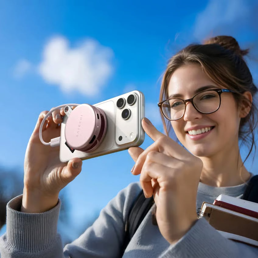 Satechi OnTheGo 5-i-1 Neo Rouge USB-C-hub i lyserød, rund udformning, monteret på bagsiden af en smartphone, til synlig udendørs brug.