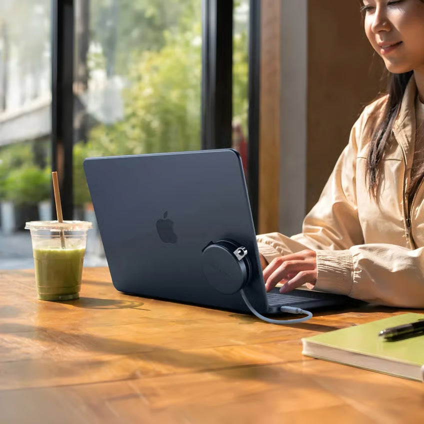 MacBook Neo med tilsluttet OnTheGo 5-i-1 Neo USB-C-hub i farven Indigo på bordet; hubben ses ved siden af den bærbare computer og en isdrink.