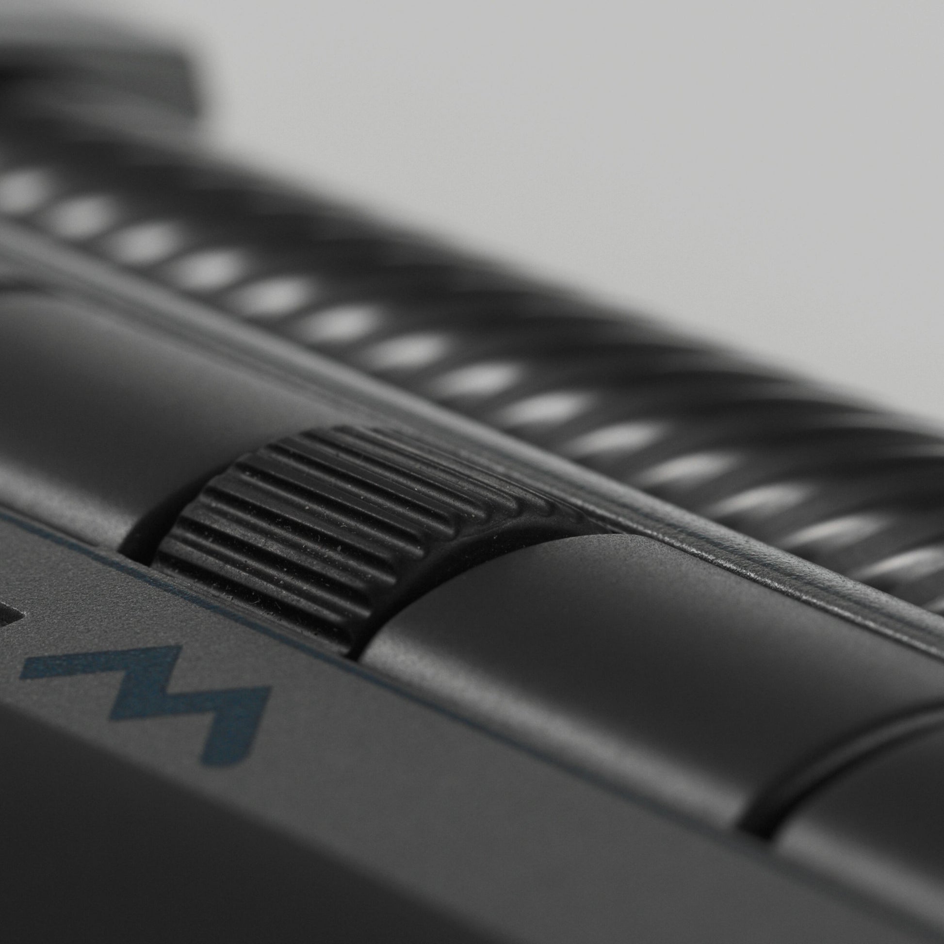 Mousetrapper Delta Extended ergonomisk mus, nærbillede af rillet kontrolhjul med blåt "M" og programmerbare knapper.