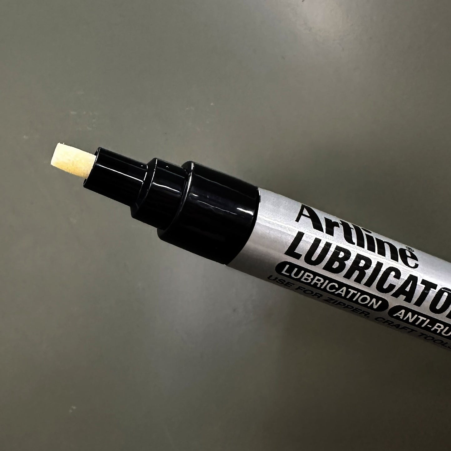 Artline Smøremiddelpen med skrå spidser, præcis smøring og anti-rust, nærbillede på grå baggrund.