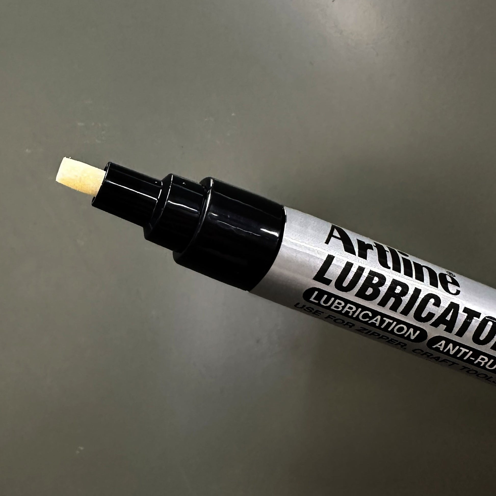 Artline Smøremiddelpen med skrå spidser, præcis smøring og anti-rust, nærbillede på grå baggrund.
