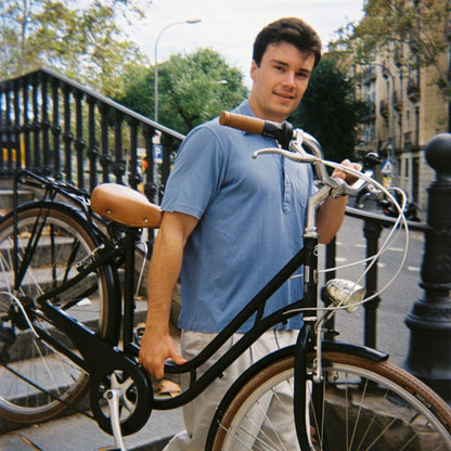 Fujifilm QuickSnap Flash Engangskamera 27 billeder viser sort cykel med brune styr holdt af mand i blå skjorte udendørs.