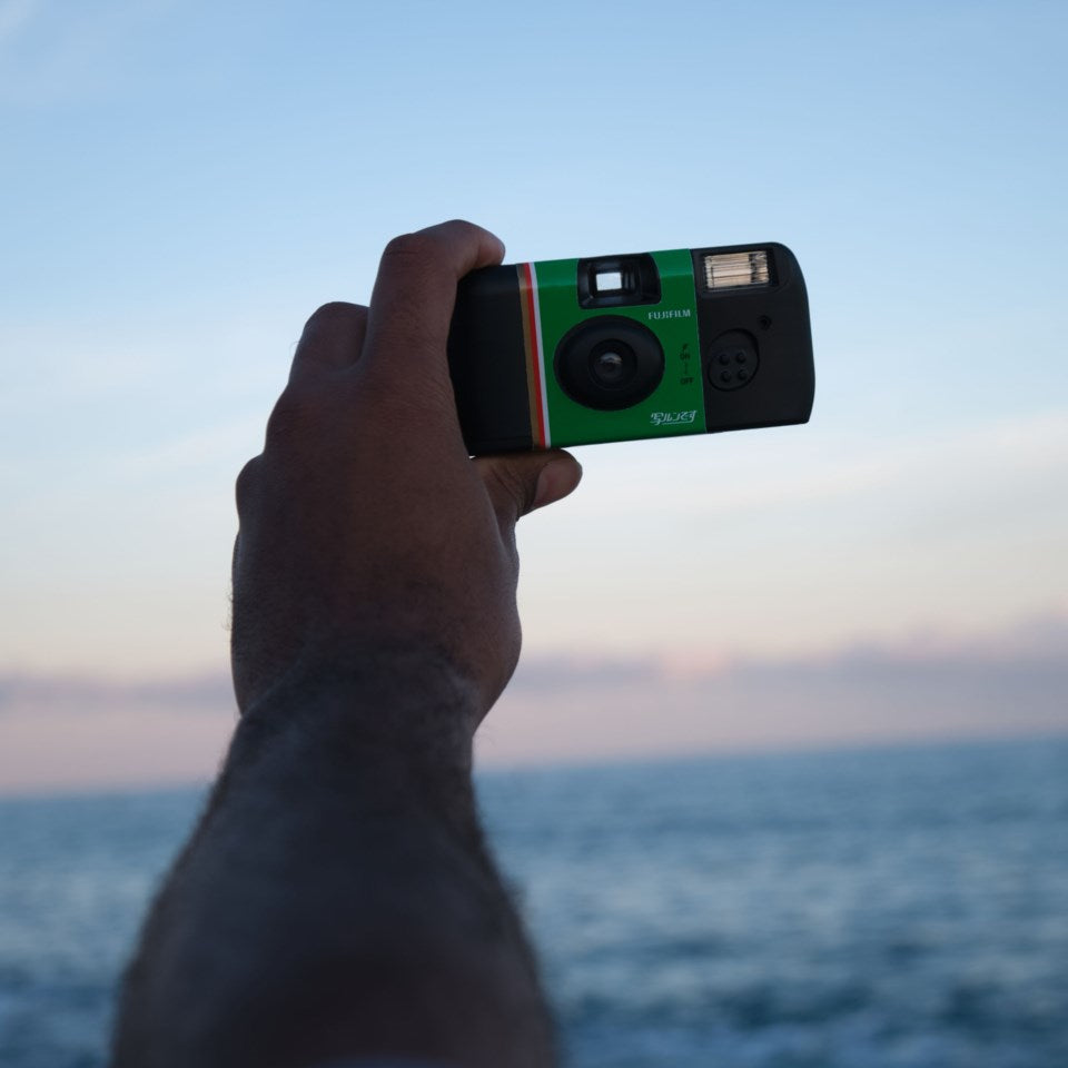 Fujifilm QuickSnap Flash engangskamera 27 billeder holdt op mod himlen, har baggrund.