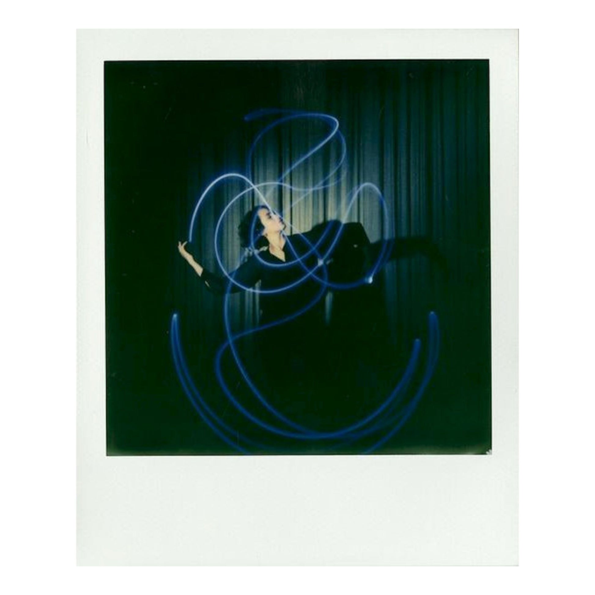 Person i mørkt tøj omgivet af blå lysspor fotograferet på Polaroid Farve film til Polaroid Now og Onestep 2 i-Type.