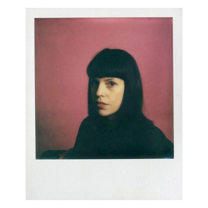 Kvinde med sort hår og pandehår, set fra siden mod kamera, fotograferet på Polaroid i-Type Farvefilm til Now og OneStep 2.