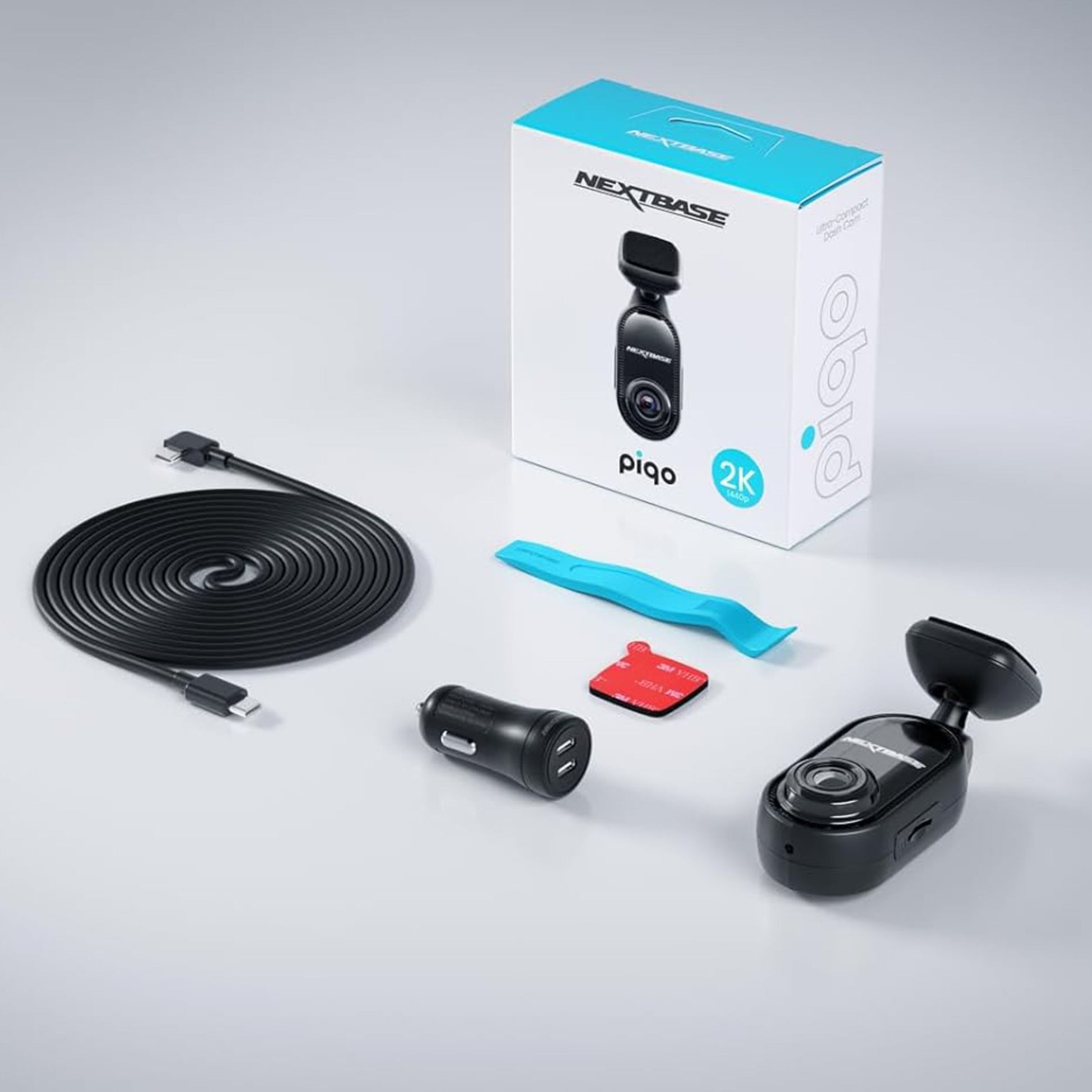 Nextbase Piqo 2K dashcam sæt med kamera, lang USB-kabel, biloplader, klæbemount, blåt værktøj og æske.