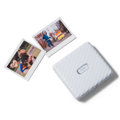Fujifilm Instax Link Wide Hvid printer med to Instax Wide billeder, et barn med voksen og et barn med fødselsdagskage.