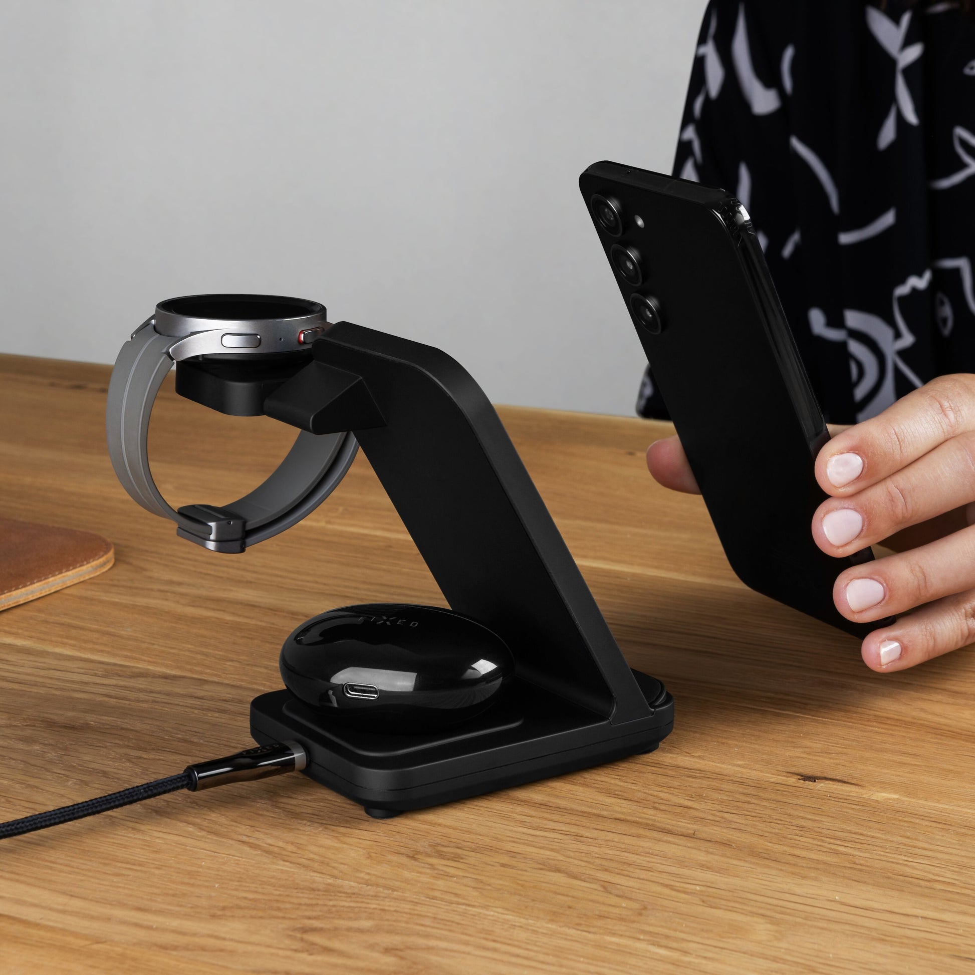 Fixed Powerstation 3-i-1 Opladningsstation oplader smartphone, Samsung Watch og trådløse ørepropper på træskrivebord.