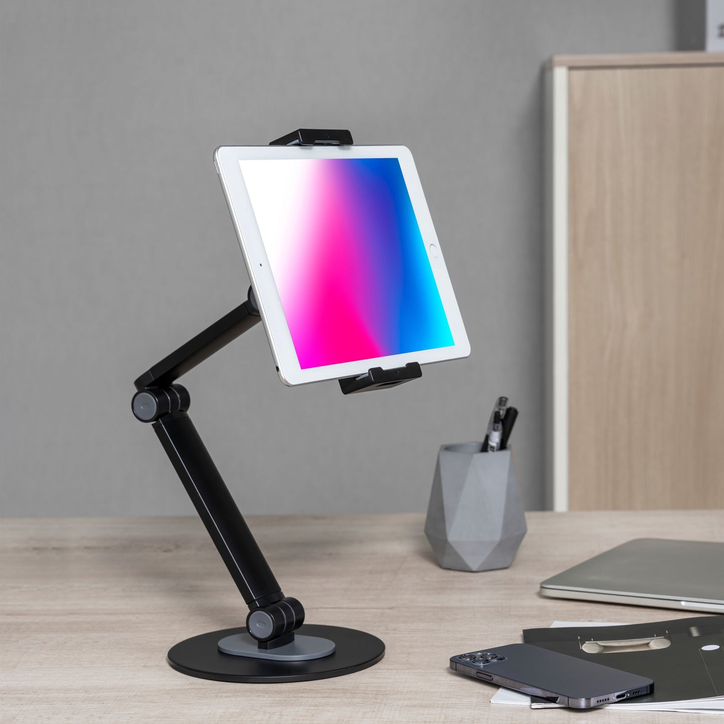 Hvid tablet med farverig skærm på drejeligt beslag til mobil/tablet 4,7-12,9". Justérbar højde, 360° rotation.