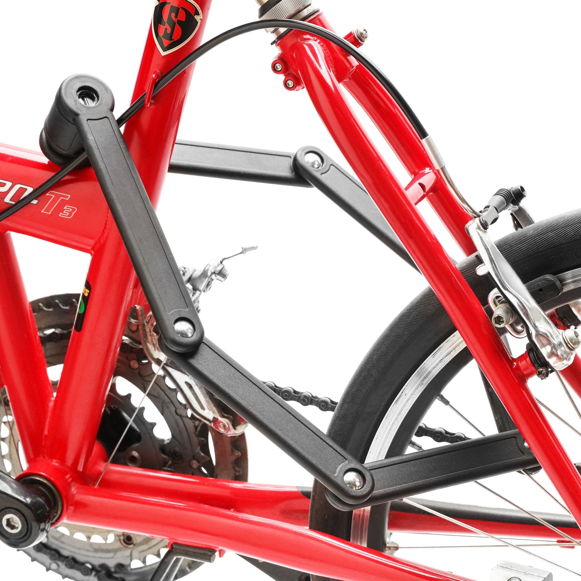 Luxorparts foldbart cykellås med nøgle monteret ved stel, tæt på sort baghjulsophæng, bremse og gear på rød cykel.