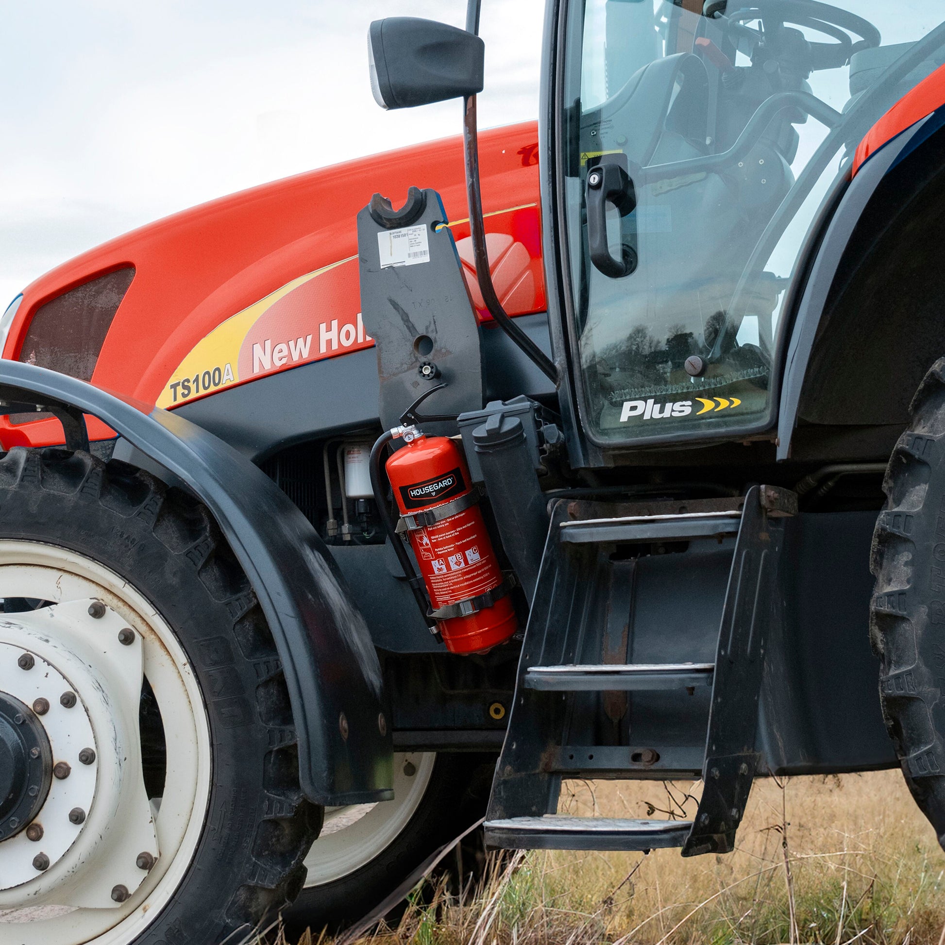 Housegard brandslukker pulver 6 kg rød monteret ved indstigningstrin til førerhus på New Holland TS100A Plus traktor.