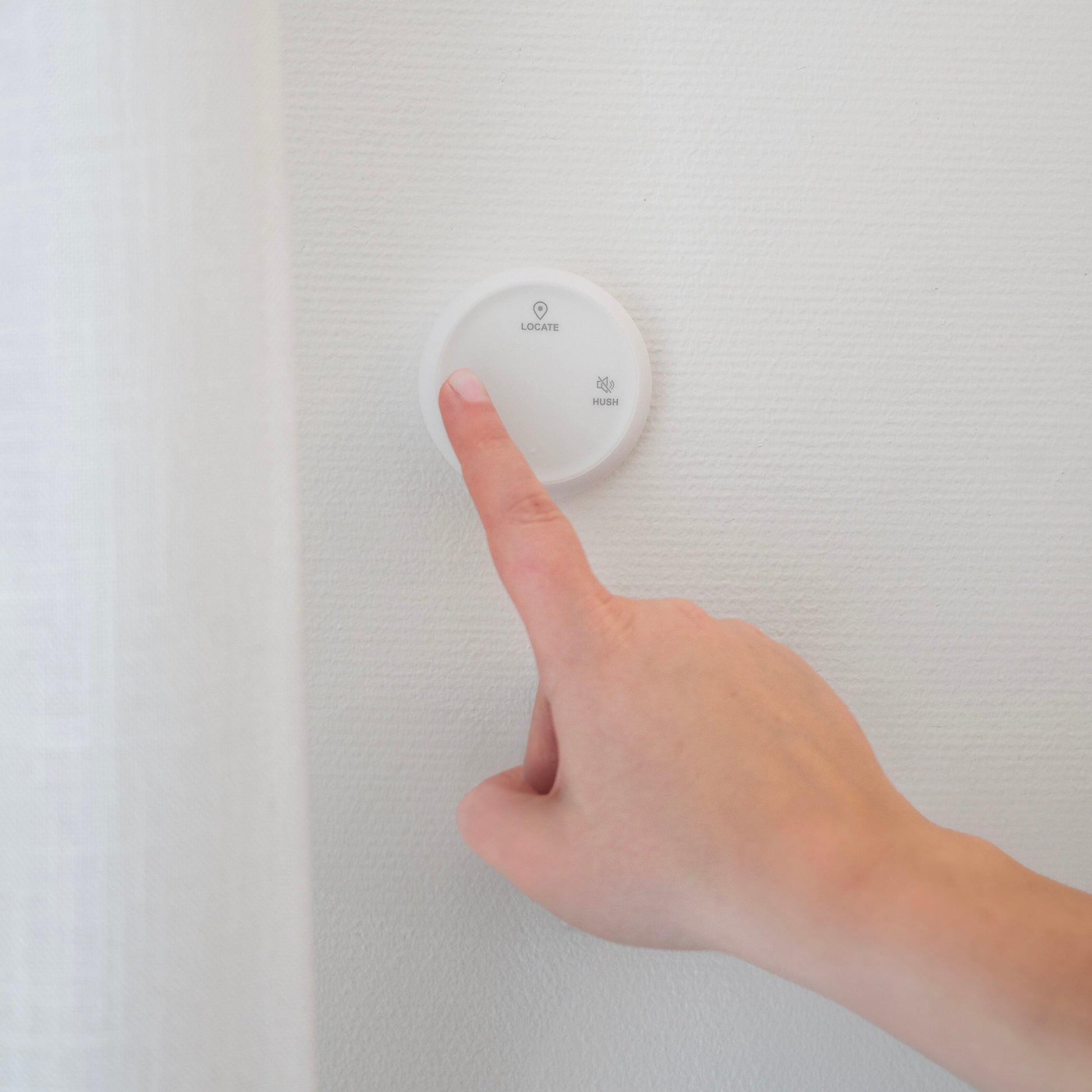 Housegard Luma trådløs fjernbetjening, rund og hvid, monteret på væg, med LOCATE og HEALTH knapper.