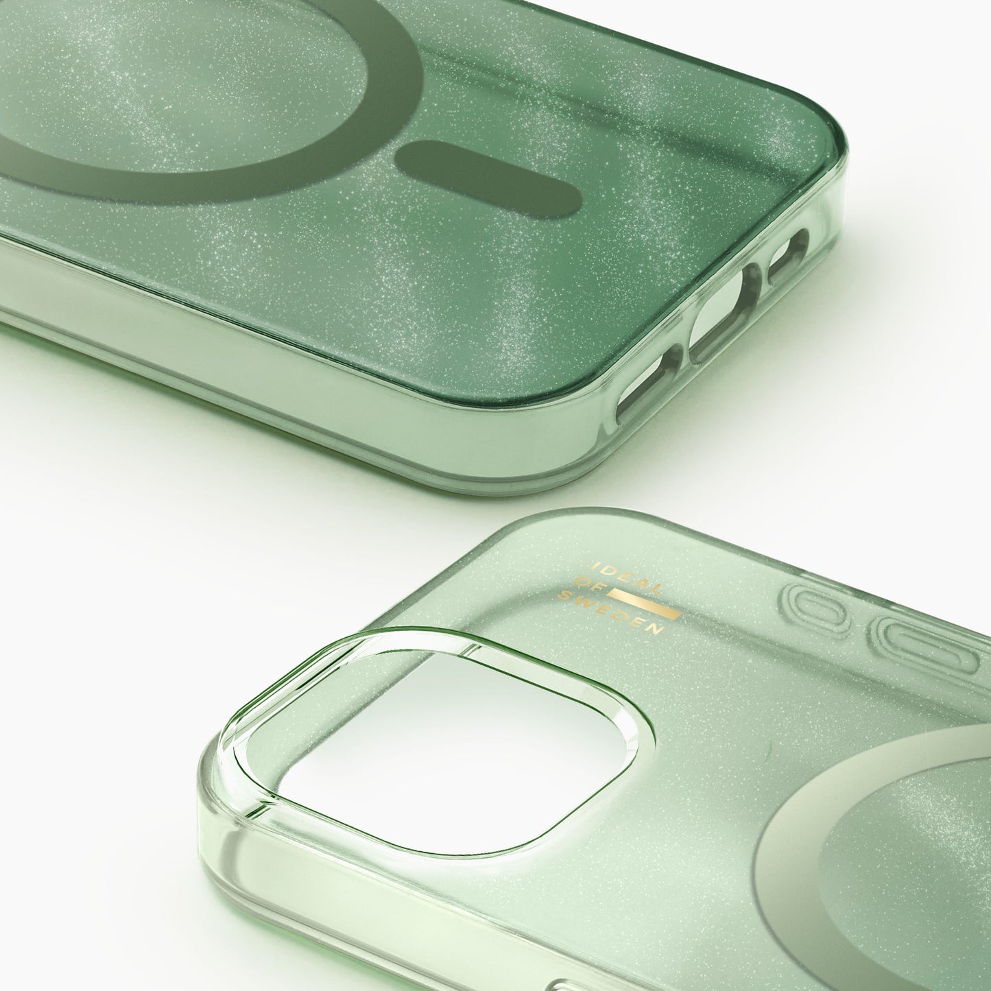 At sagegrønne gennemsigtige Ideal of Sweden MagSafe covers til iPhone 13-16e med runde kanter og guldlogo ved kamerahul.