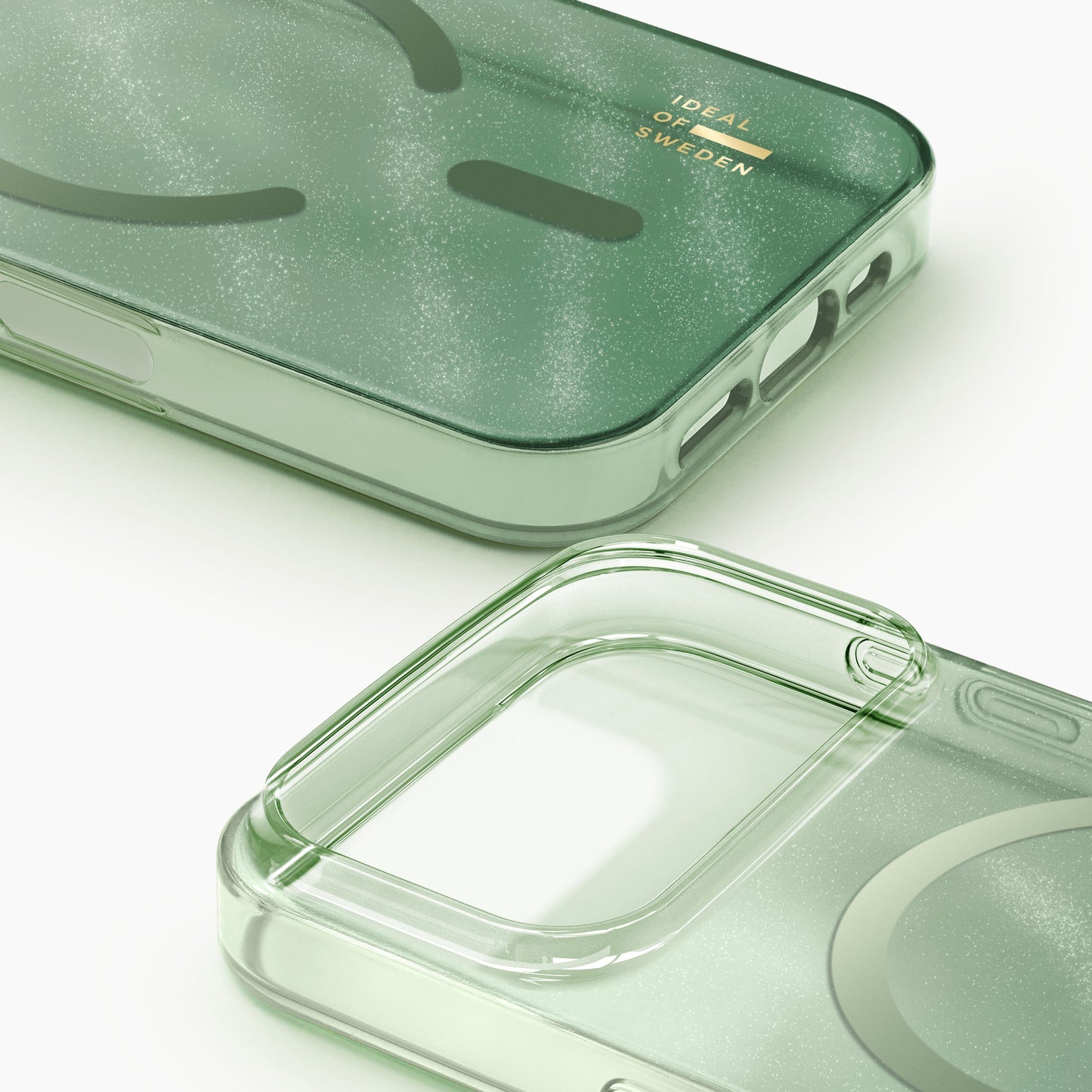 To Sage Green IDEAL OF SWEDEN Klare MagSafe-covers til iPhone 17 Pro med glitter-effekt, klar bagside og guldfarvet logo.