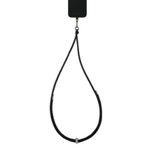 Sorter smartphone med IDEAL OF SWEDEN Cord Phone Strap justerbar mobilrem med metalspænder, hænger lodret.