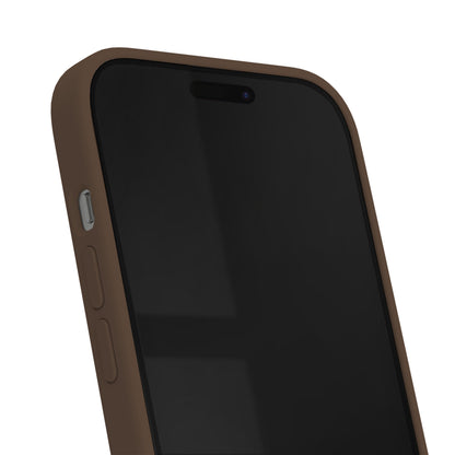 IPhone i IDEAL OF SWEDEN Silicone MagSafe Cover Mocha Mousse, sideknapper og sort skærm med vinduesrefleksion synlig.