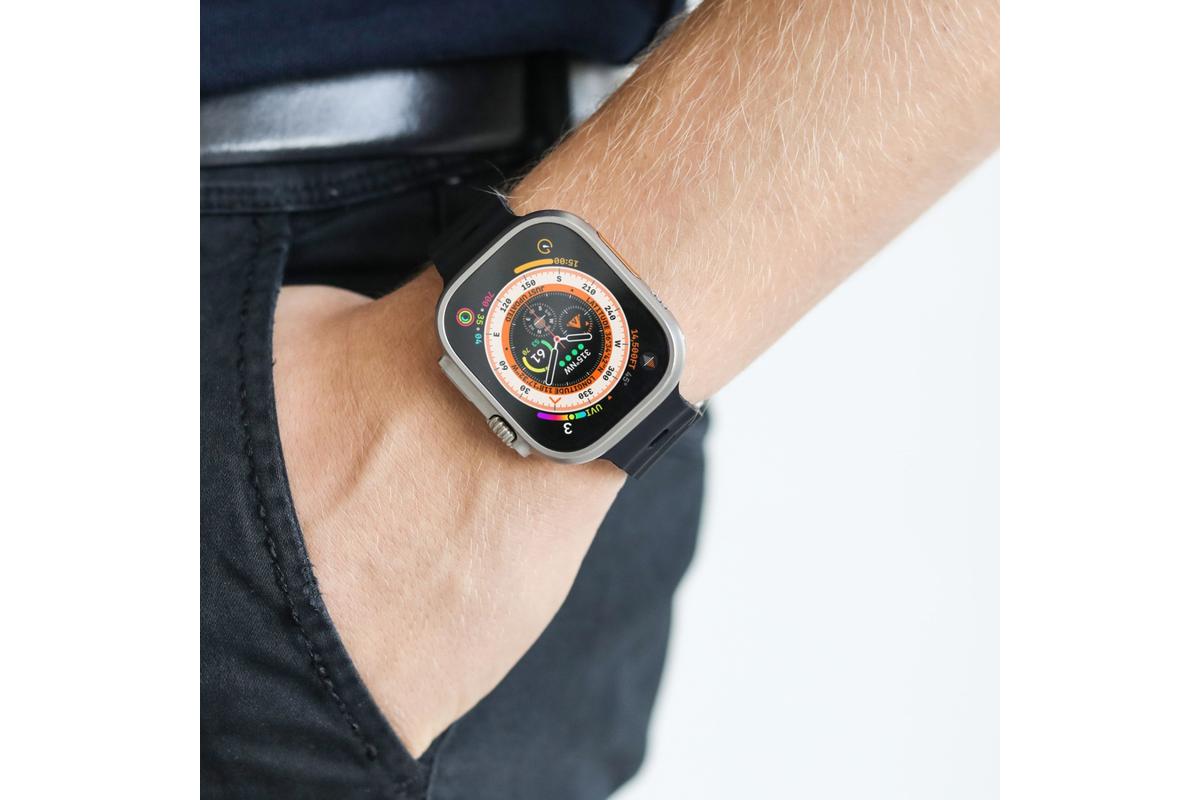 Apple Watch med farverig urskive og Vonmählen Wave Band 2 rem i sort, ses på hånd i lommen på mørke bukser.