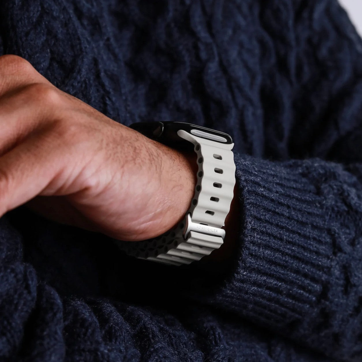 Vonmählen Wave Band 2 til Apple Watch, creme, ses på håndled, person i mørkeblå sweater med armene over kors.
