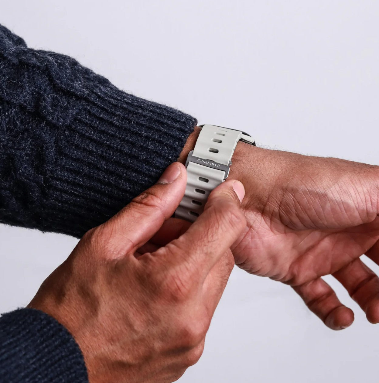 Cremefarvet Vonmählen Wave Band 2 monteres på Apple Watch af person i mørkeblå striktrøje.
