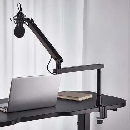 Deltaco lavprofil mikrofonarm sort med monteret mikrofon på justerbar arm, laptop og lukket notesbog på mørkt skrivebord.