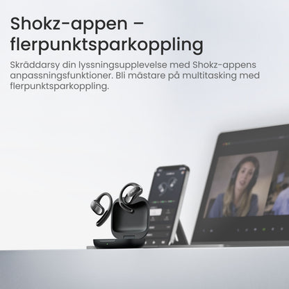 Shokz OpenFit Air trådløse øretelefoner sorterer i opladeetui, svensk tekst om multipoint-forbindelse på baggrund.