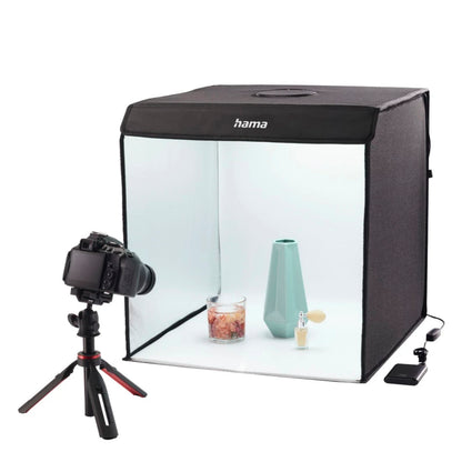 Hama Mini-fotostudie ToGo med LED-ringlys, sort med halvgennemsigtig front, viser oplyst turkis vase, duftlys og parfume.