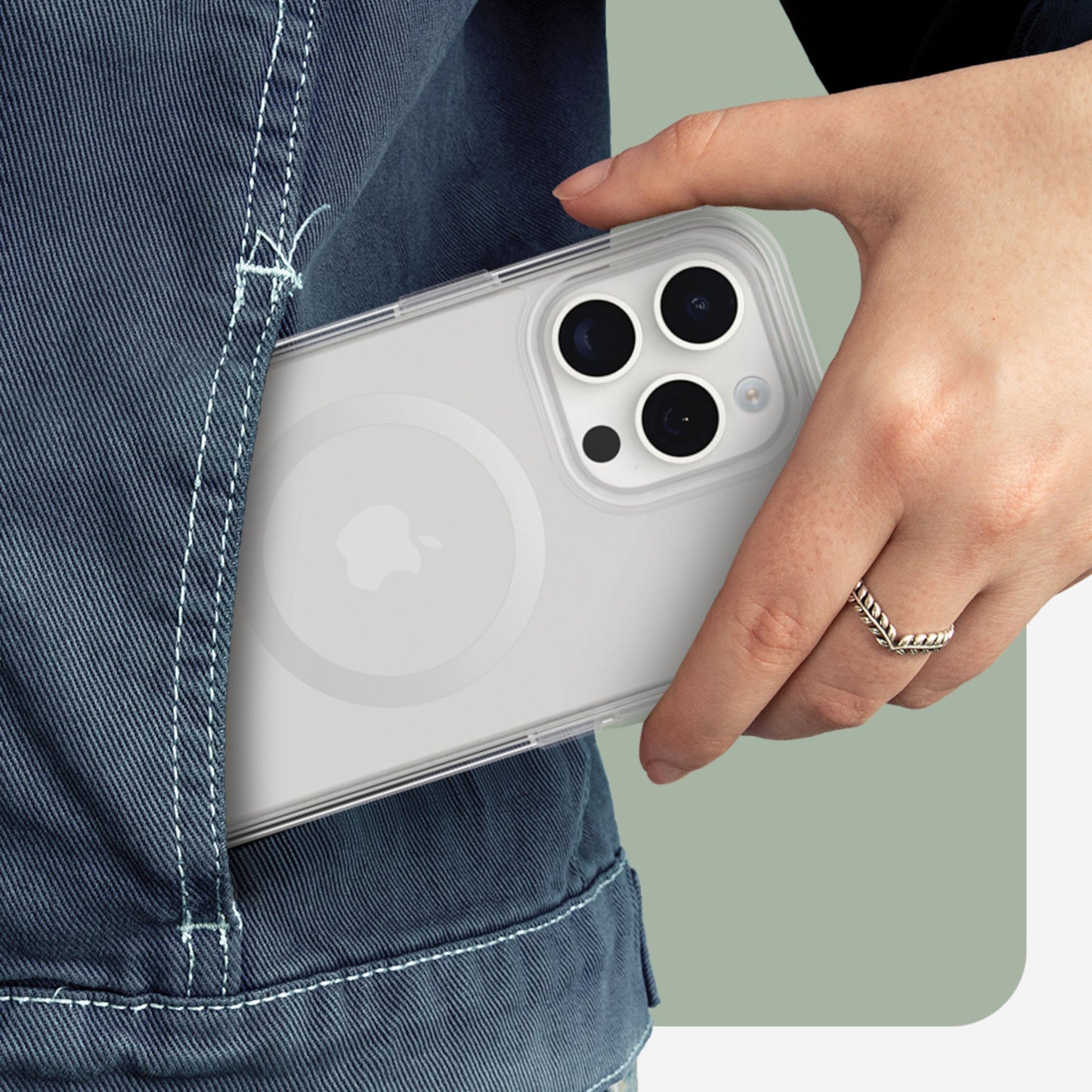 IPhone 15 Pro med klar MagSafe Symmetry cover, kamera og MagSafe cirkel synlig, skubbes i baglomme af blå denim.