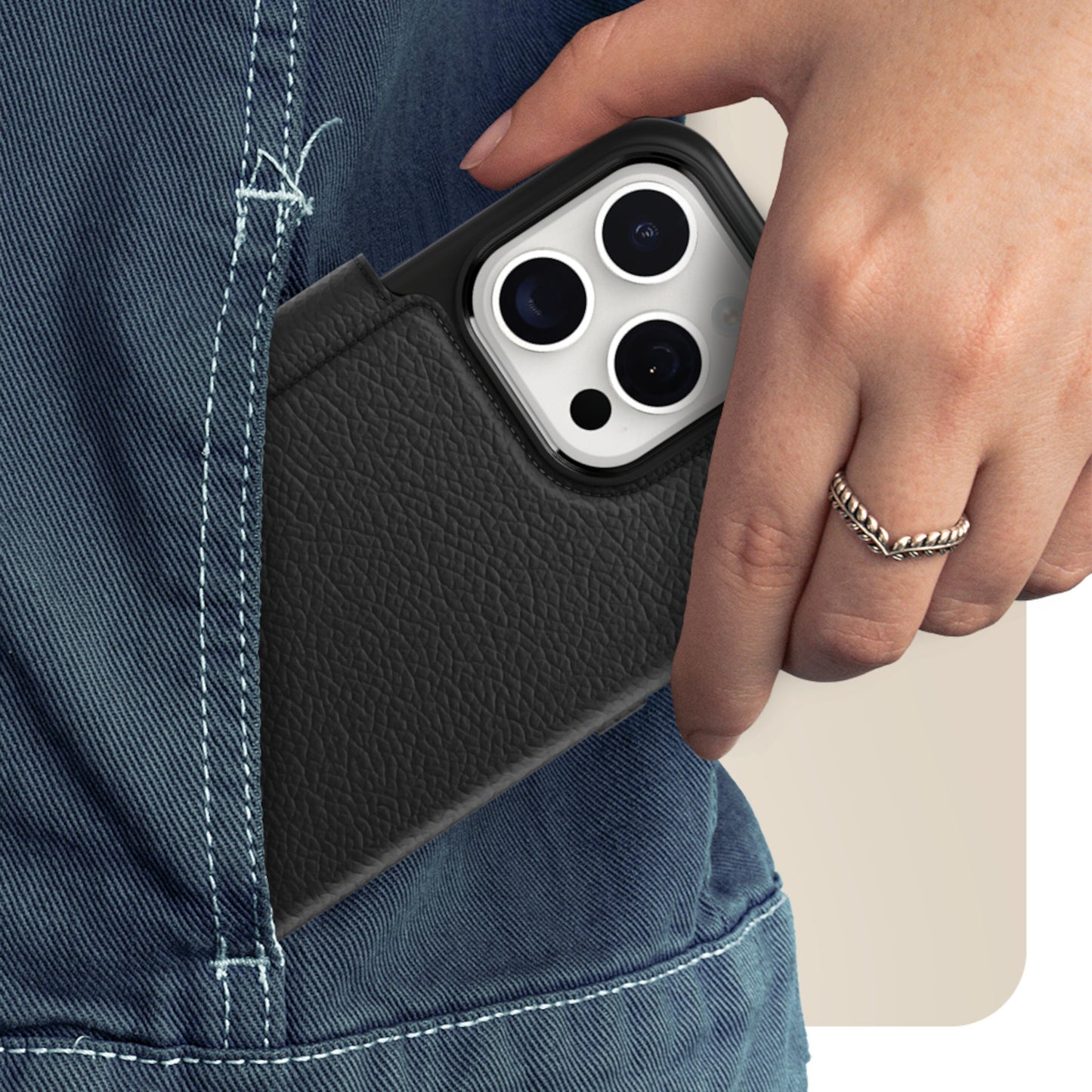 IPhone 15 Pro i Otterbox Strada med MagSafe cover glider ned i baglomme på blå jeans, hånd med sølvring.