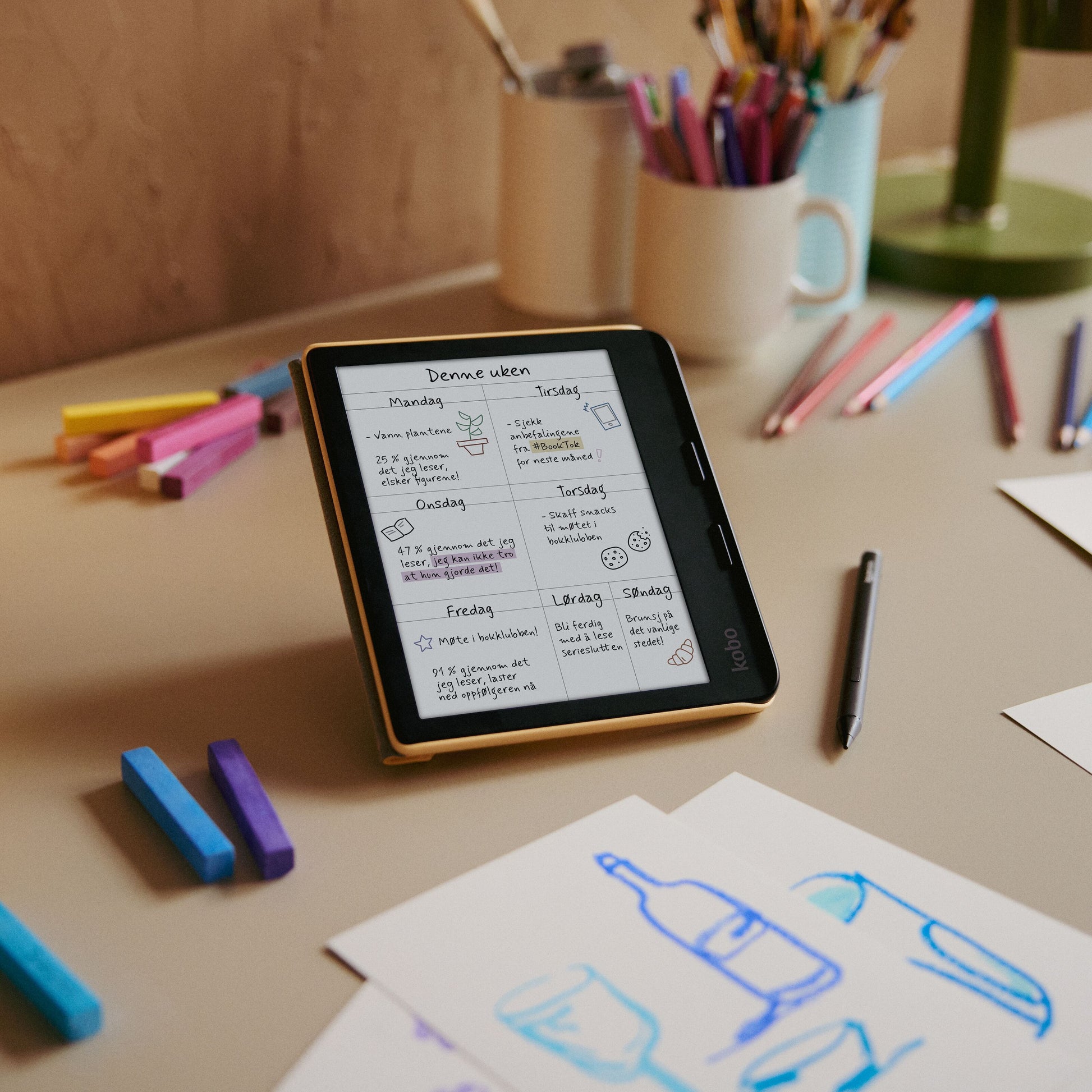 Kobo Libra Colour 7" e-bogslæser med ugentlig planner på skærmen, E Ink Kaleido 3, skrivebord, farvede blyanter.