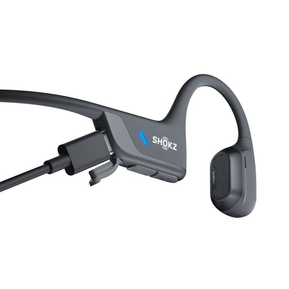Shokz OpenRun Pro 2 trådløse hovedtelefoner sort, Bluetooth 5.3, tilsluttet opladerkabel, blå LED lyser.