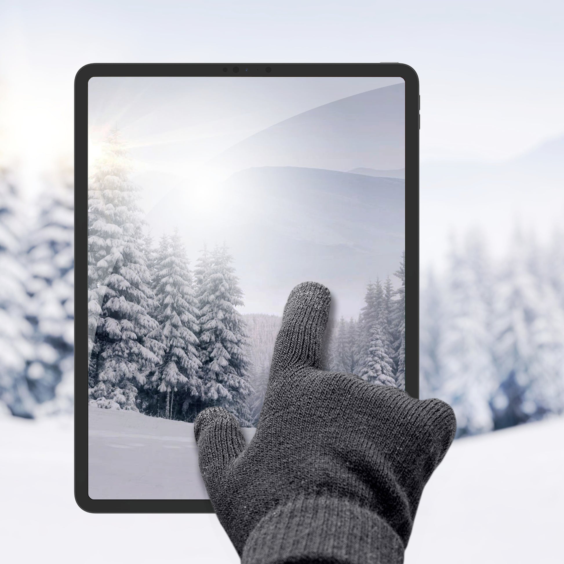 Linocell Strikkede touchskindhandsker sorterer bruges på tablet med vintermotiv, sne og grantræer ses på skærmen.