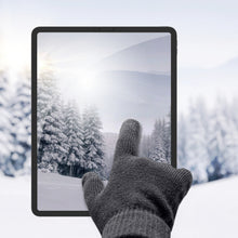 Linocell Strikkede touchskindhandsker sorterer bruges på tablet med vintermotiv, sne og grantræer ses på skærmen.