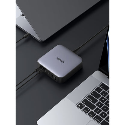 Ugreen Kraftfuld Multilader 6 porte 200 W sølv tilsluttet til laptops, flere kabler i siden.