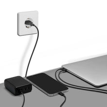 Linocell Premium GaN Multioplader PD 3.0 100W sort med USB-C tilsluttet smartphone og lukket laptop på grå overflade.