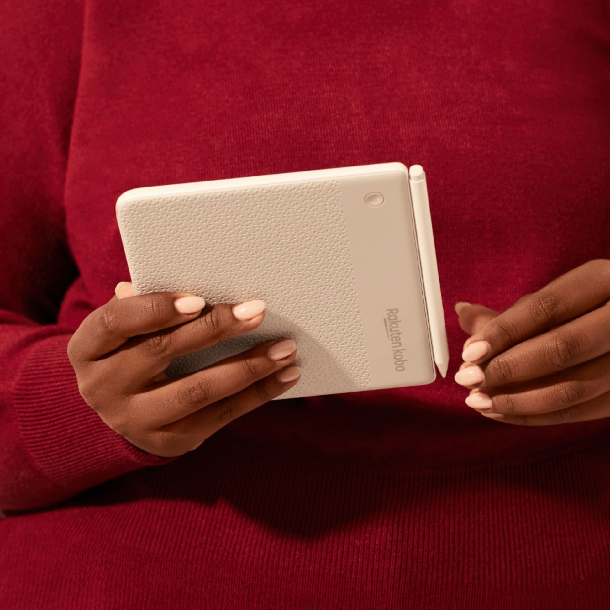 Kobo e-læser i hvid med tekstureret bagside, synligt Kobo-logo og USB-C port, holdt i hånd.