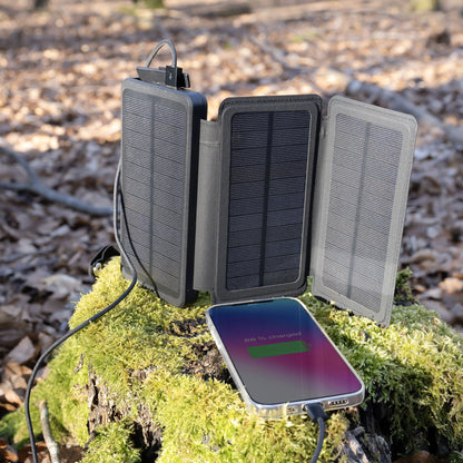 Linocell powerbank med solcelle, 20 W, 8000 mAh oplader smartphone på træstub i skov, batteristatus 65 vises.