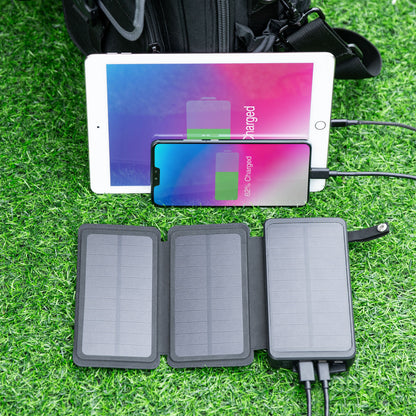 Linocell powerbank med solcelle, 20W 8000mAh, oplader tablet og smartphone via USB, rygsæk i baggrunden.
