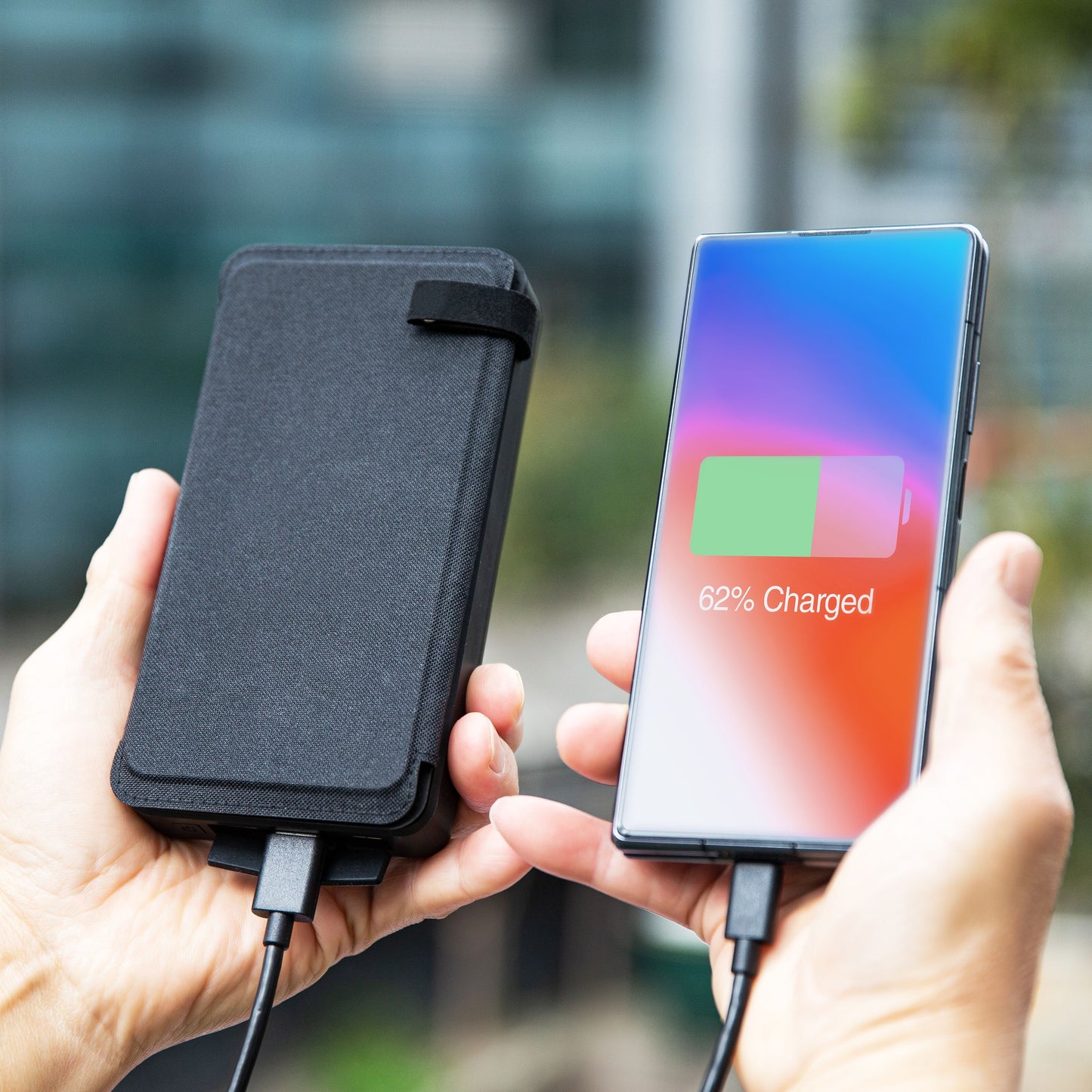 Linocell Powerbank med solcelle, 30W 16000mAh, tilsluttet smartphone med 62 batteri, udendørs baggrund sløret.