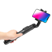 Linocell Selfiestang Pro med stativ og Bluetooth-udløser holdes i hånd med smartphone med pink og blå skærm.