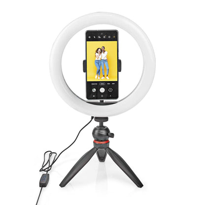 Nedis Ring Light 10" ringbelysning med stativ og USB-kontrol, holder smartphone med to personer på gul baggrund.